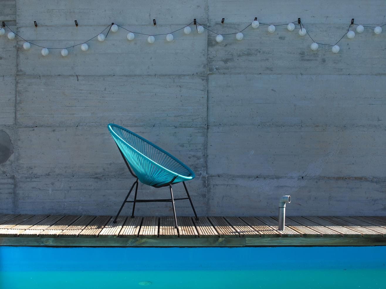 A turquoise blue chair in the midday sunlight at a pool in Spain