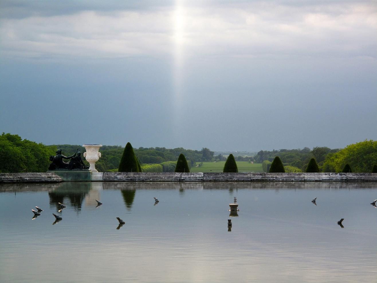 A view to a fountain in the Versailles Palace Park in France on a cloudy summers day